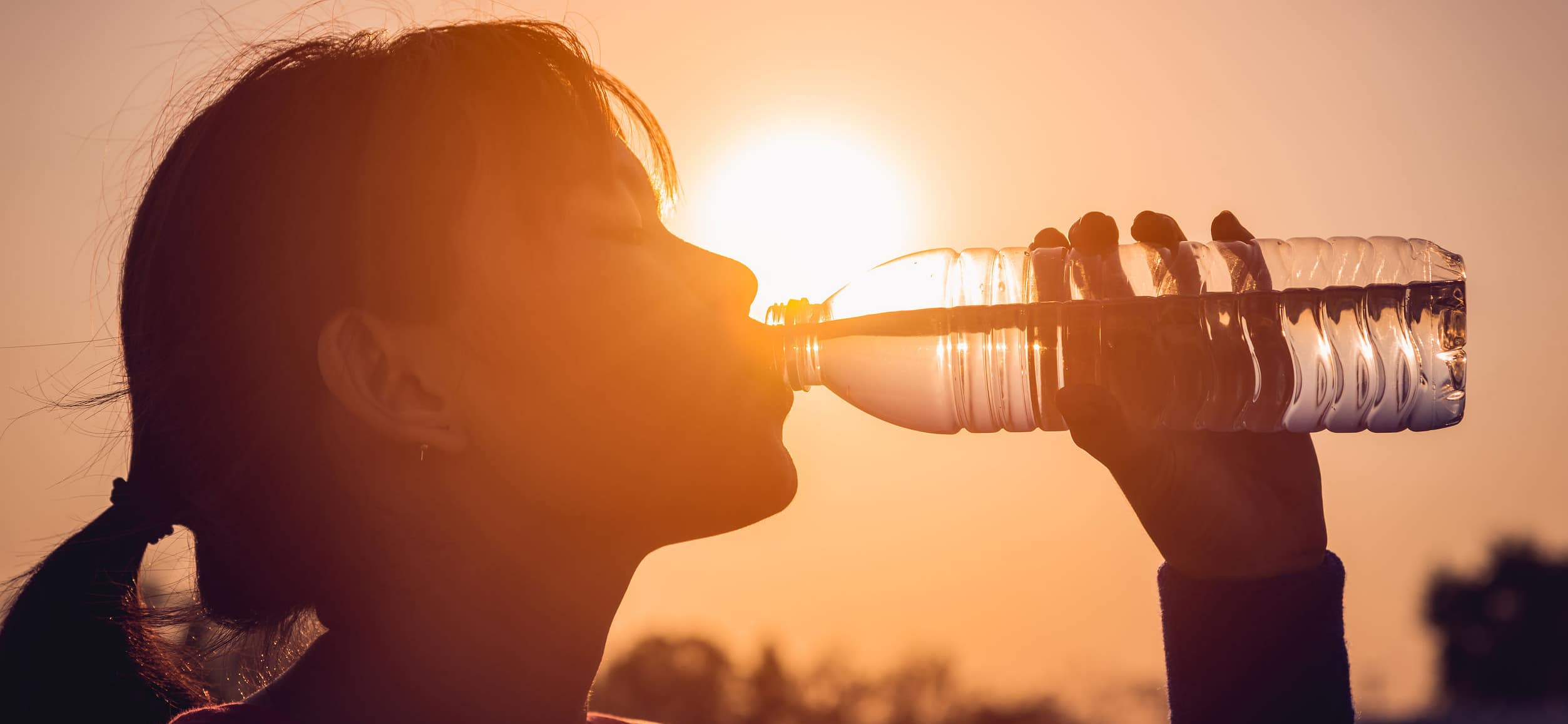 Woman out in the sun drinking a bottle of water