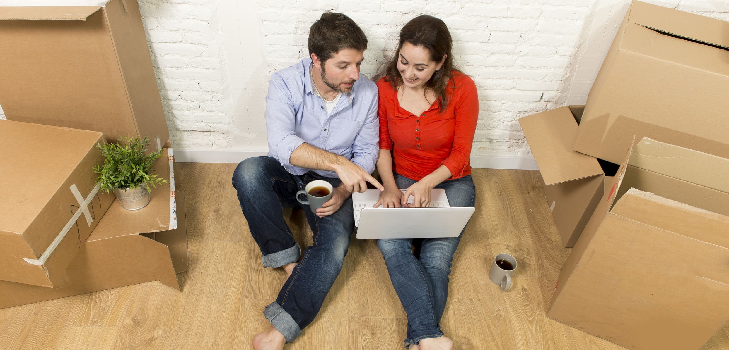 Couple on a laptop sitting by moving boxes